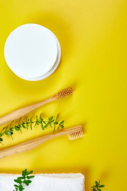 Bambu diş fırçaları ve kulak çubukları, ve sarı kağıtta yeşil yapraklar, çevre dostu, sıfır atık kişisel hijyen ürünleri, diş bakımı konsepti