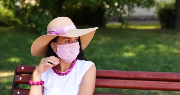 Mujer en sombrero de paja se quita la máscara protectora rosa — Vídeo de stock