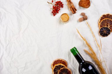 Kış mevsimi için düz malzemeler ve bir şişe kırmızı şarap beyaz tekstil keten masa örtüsü üzerinde sıcak şarap durgun yaşam, kumaş dokusu, Noel içeceği, fotokopi alanı.