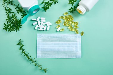 Tıbbi maske ve haplar, balık yağı, mavi arka planda vitaminler, Coronavirus COVID-19 konsepti, çeşitli ilaç hapları, tabletler ve kapsüller, bağışıklık güçlendirici..