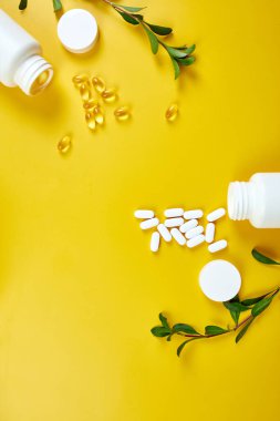 Düz tabaka haplar, balık yağı, yeşil yapraklı vitaminler sarı arka planda, sağlık konsepti, sağlıklı gıda, sağlıklı yaşam için takviyeler, bağışıklık güçlendirici..