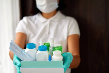 Koronovirüsün önlenmesi, güvenli ev ve karantina kavramının önlenmesi sırasında tıbbi hap alışverişi yapan maskeli ve eldivenli büyücü kadın kurye, bağış ürünleriyle gönüllü olan.