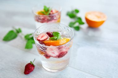 Çilekli, portakallı ve nane şekerli yaz kokteyli beyaz masada, ev yapımı ferahlatıcı limonata, çilekli punç, fotokopi alanı.