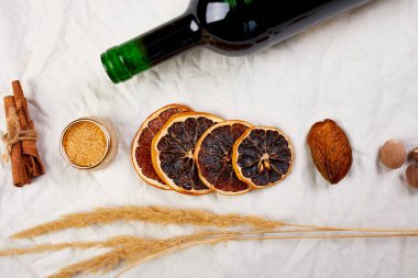 Kış mevsimi için düz malzemeler ve bir şişe kırmızı şarap beyaz tekstil keten masa örtüsü üzerinde sıcak şarap durgun yaşam, kumaş dokusu, Noel içeceği, fotokopi alanı.