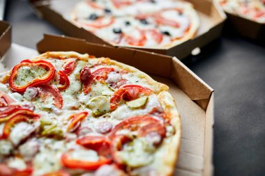 Siyah zemin üzerinde dilimlenmiş sıcak İtalyan pizzası olan kutuyu aç.