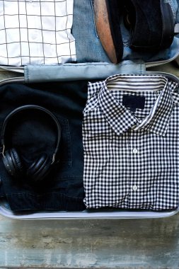 Sıradan erkek eşyalarıyla evde bavul hazırlamak.