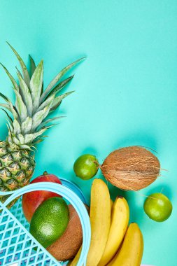 Mavi arka planda organik egzotik meyvelerle marketten alışveriş torbası..