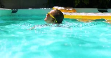 Yüzme havuzunda mavi dalış maskesi takan sevimli, mutlu bir kız çocuğu.