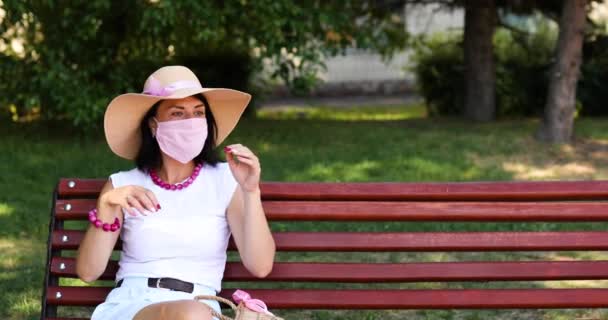 Kvinna i halmhatt tar av rosa skyddsmask — Stockvideo