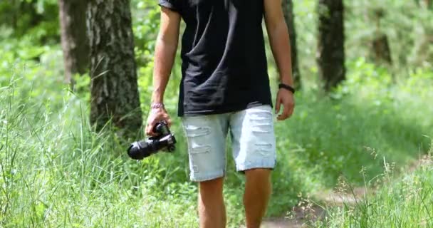 Man fotograaf met een foto camera in de hand lopen outdoor — Stockvideo