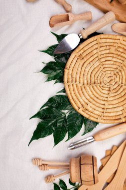 Yeşil yapraklı ahşap mutfak aletleri, tekstil arka planında yemek pişirme araçları, yemek blogları ve sınıf konsepti, yukarıdan alınan ktchenware koleksiyonu, maket, çerçeve.