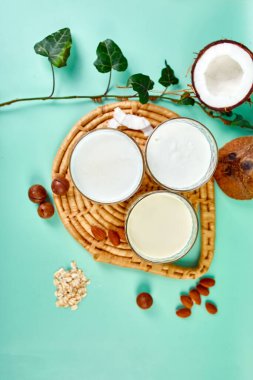 Çeşitli vejetaryen bitki içerikli süt ve malzemeler, süt içermeyen süt, mavi arka planda alternatif türde vejetaryen sütleri, düz bir zemin, fotokopi alanı olan üst görünüm