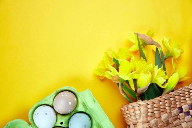 Yaratıcı Top View düz yatar bahar kompozisyonu saman torbası narsis çiçek buketi, sarı arka planda paskalya yumurtası, mutlu Paskalya kutlamaları.