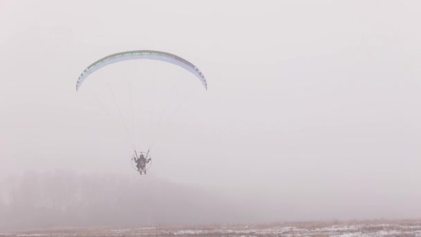 Landing met paraglider paramotor gliding in mist — Stockvideo
