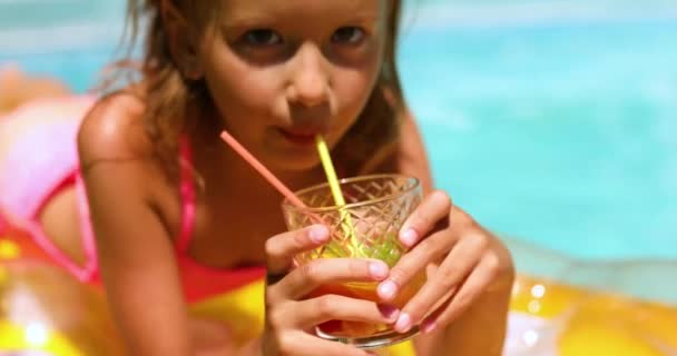 Liten flicka avkopplande i poolen, njuta av suntans, dricka en juice på uppblåsbar gul madrass — Stockvideo