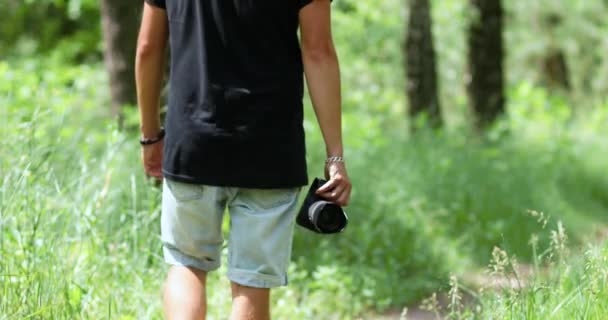 Man fotograaf met een foto camera in de hand lopen outdoor — Stockvideo