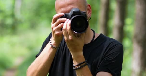 Мужской фотограф фотографируется с профессиональной камерой на открытом воздухе — стоковое видео