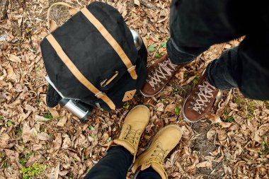 Yürüyüş botları içinde modern genç bir çift seyahat çantasıyla ormanda duruyor, açık hava seyahati konsepti, üst manzara, sonsuza dek aşk, sevgililer günü.