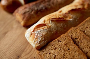 Ahşap bir yüzeyde çeşitli ekmek türlerinin üst görüntüsü. Ev yapımı ekmek, küçük fırın, doğal tarım ürünleri, yerel gıda, yerli üretim kavramı. Sağlıklı ve lezzetli organik yiyecekler.. 