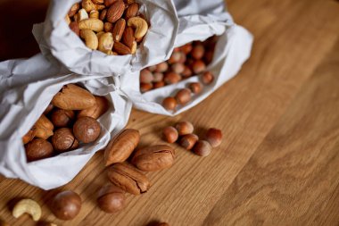 Masanın üstünde, tahta arka planda bir kese kağıdının içinde çeşitli fındıklar, market konsepti, fındık teslimatı, sıfır atık yiyecek alışverişi. Boşluğu kopyala.