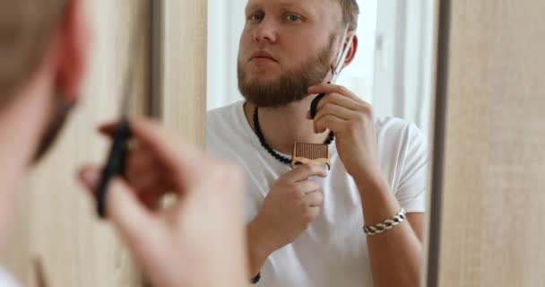 穿着白色T恤的英俊男人在家里梳理和修剪胡子 留着胡子 隔离期间的自我照顾 呆在家里 — 图库视频影像