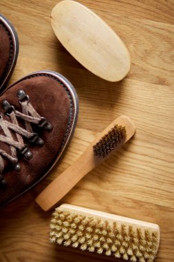 Düz yatış, üst görünüm ayakkabılar süet ayakkabı bakım aksesuarları, ahşap masada fırça. Ayakkabı bakımı yakalandı, metin için kopyalama alanı.