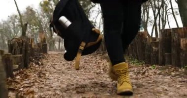 Ormanda dışarıda yürüyen çizmeli kadın bacakları, ahşap, seyahat, ellerinde kamp çantası, vahşi doğada sırt çantası. Seyahat tutkusu