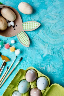 Mavi arka planda fırçalı, boyalı ve dekoratif elementli yumurta paketleri. Uzayı kopyala, Mutlu Paskalyalar, DIY, düz yat.