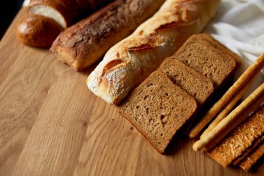 Ahşap bir yüzeyde çeşitli ekmek türlerinin üst görüntüsü. Ev yapımı ekmek, küçük fırın, doğal tarım ürünleri, yerel gıda, yerli üretim kavramı. Sağlıklı ve lezzetli organik yiyecekler..