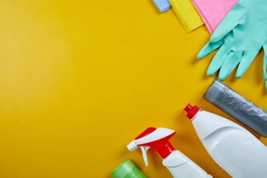Fotokopi alanı olan sarı masa üzerindeki ev temizleme ürünleri, farklı yüzeyler için temizlik seti, Deterjan servis konsepti, Top view.