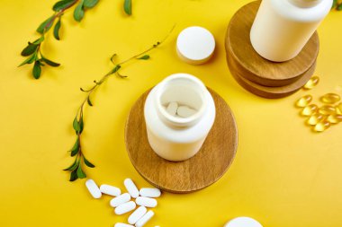 Düz tabaka haplar, balık yağı, yeşil yapraklı vitaminler sarı arka planda, sağlık konsepti, sağlıklı gıda, sağlıklı yaşam için takviyeler, bağışıklık güçlendirici..