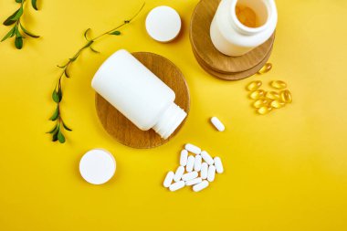 Düz tabaka haplar, balık yağı, yeşil yapraklı vitaminler sarı arka planda, sağlık konsepti, sağlıklı gıda, sağlıklı yaşam için takviyeler, bağışıklık güçlendirici..