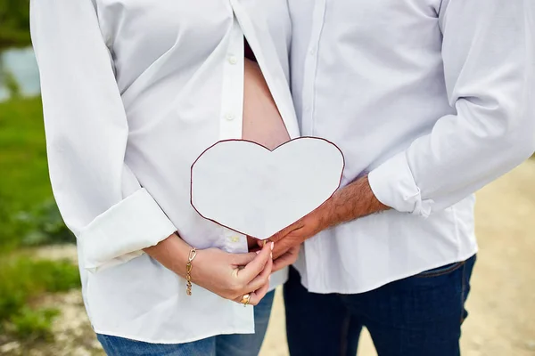 Unrecognizable couple, future parents, pregnant young woman and a man touching belly, waiting for a miracle, Pregnant tummy close up, outdoor in spring or summer park