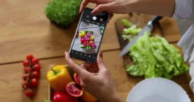 Sağlıklı salatanın fotoğrafını çeken kadın akıllı telefonuyla mutfaktaki blogu için, yemek blogcusu konsepti, sağlıklı yaşam tarzı.