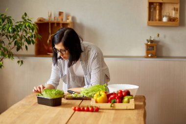 Kadın evde mutfakta yemek pişiriyor, dijital tablet veya akıllı tablet kullanıyor, yemek tarifi arıyor, sağlıklı gıda konsepti, vegan ya da diyet yapıyor..