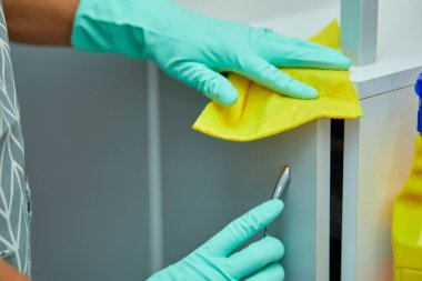 Sakallı adam masa yüzeyini havlu ve eldivenle temizliyor, dezenfektan sprey şişesi, cinsiyet ayrımcılığı klişelerini kırıyor, cinsiyet ayrımı yapmıyor..