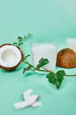 Mavi arka planda bir bardakta taze hindistan cevizi sütü, alternatif türde vegan sütü, organik sağlıklı içecek konsepti..