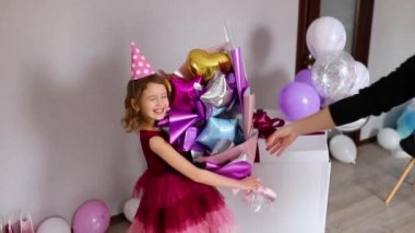 Yavaş çekimde doğum günü kızını tebrik eder ve ona çok renkli bir balon buketi verir. Mutlu, tatlı çocuk..
