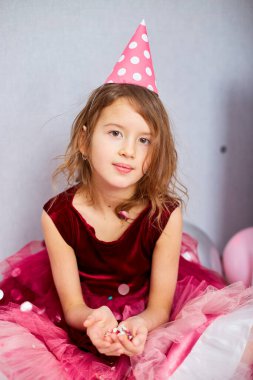 Güzel küçük kız çok renkli konfetileri havaya uçuruyor, evde doğum günü partisinde eğleniyor. Mutlu yıllar çocuğum..