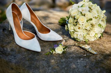 Düğün aksesuar seti, kadın klasik ayakkabılar, alyanslar ve doğal taştan arka planda nişan yüzüğü..