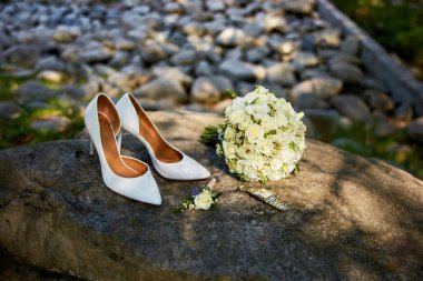 Düğün aksesuar seti, kadın klasik ayakkabılar, alyanslar ve doğal taştan arka planda nişan yüzüğü..