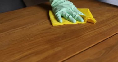 Lateks eldivenli, mikrofiber bezli, tahta masa yüzeyini temizleyen, evde masa temizleyen, günlük ev temizliği yapan, tanınmayan bir kadın..