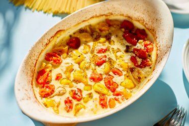 Fırında domatesler ve makarna ile feta 'nın popüler viral tarifi, mavi arka plandaki Fetapasta güneş ışığı, sert ışık. Yeni, popüler yemek yemeği, Top view, kopyalama alanı