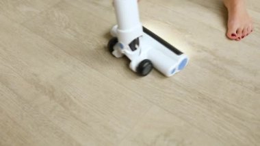 Evde temizlik yaparken modern elektrik süpürgesi kullanan tanınmayan bir kadın, günlük ev temizliği rutini yapıyor..