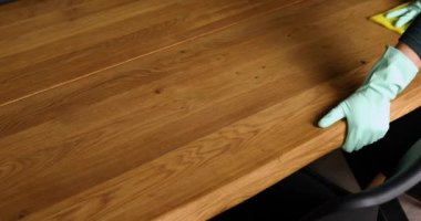 Lateks eldivenli, mikrofiber bezli, tahta masa yüzeyini temizleyen, evde masa temizleyen, günlük ev temizliği yapan, tanınmayan bir kadın..