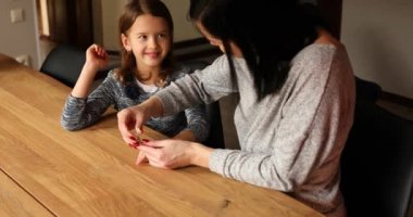 Anne, kızlarının tırnaklarını makasla kesmeye yardım ediyor. Kadın, çocukların tırnaklarını kesiyor. Aile sevgisi ve bakımı.