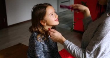 Anne evde kızının saçını tarıyor, kadın ve kız gülümsüyor, sevgi, sevgi dolu aile anları, birlikte vakit geçiriyor..