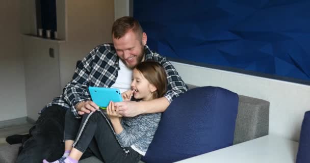 Padre feliz con su hija usando tableta en la sala de estar, en el sofá en casa — Vídeos de Stock