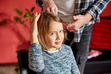 Babası tarıyor, kızının saçını evde tarıyor, çocuk saç çekme hakkında surat yapıyor, kızgın kız acı çekiyor, aile anları yaşıyor, birlikte zaman geçiriyor..