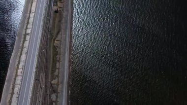 Mavi nehir boyunca giden arabaların olduğu asfalt bir yolun insansız hava aracı manzarası. Yukarıdan bak, köy yolunun havadan görünüşü.